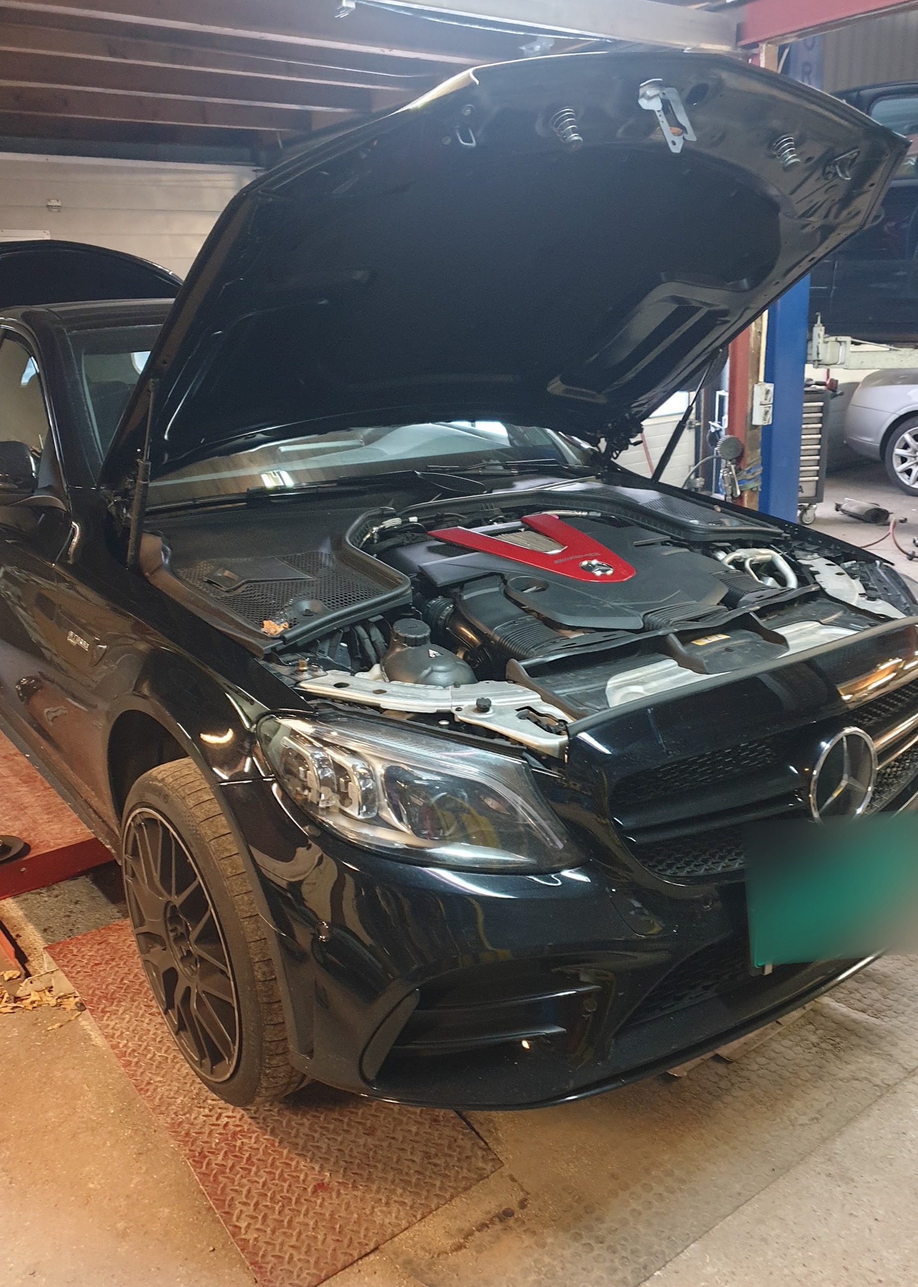 Zwarte Mercedes met open motorkap op de brug
